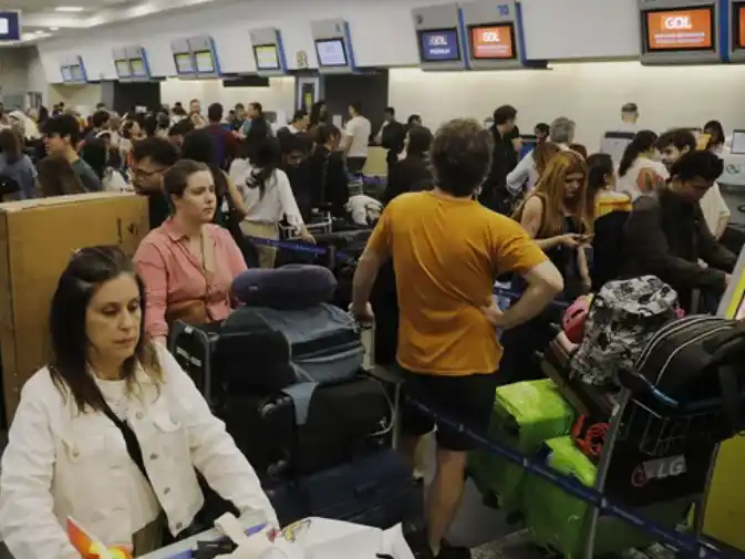 Pasajeros esperando en un aeropuerto argentino frente a pantallas con vuelos cancelados.