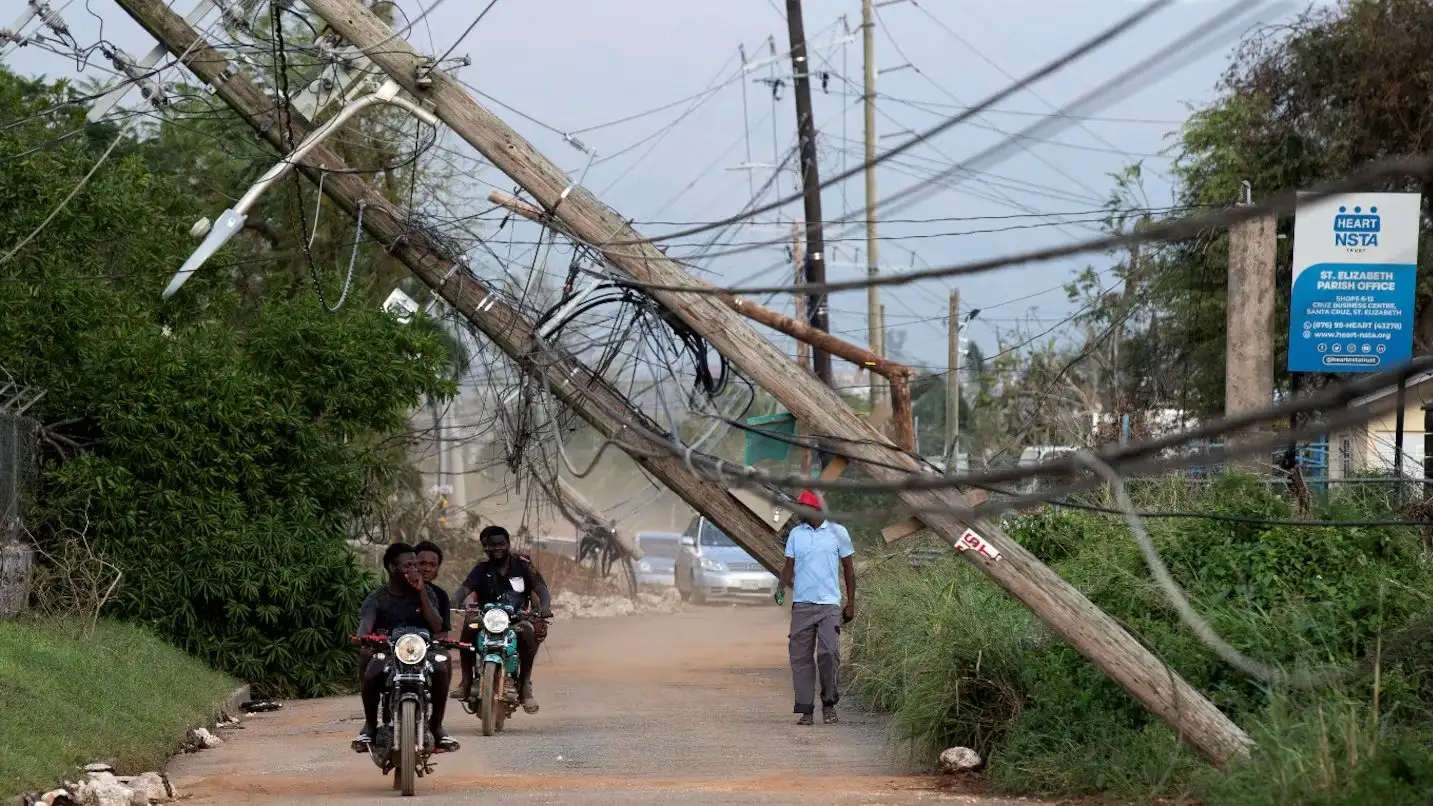Personas recorren una calle afectada por el paso del huracán Melissa este jueves, en Santa Cruz (Jamaica). (Foto: EFE/ Orlando Barría).