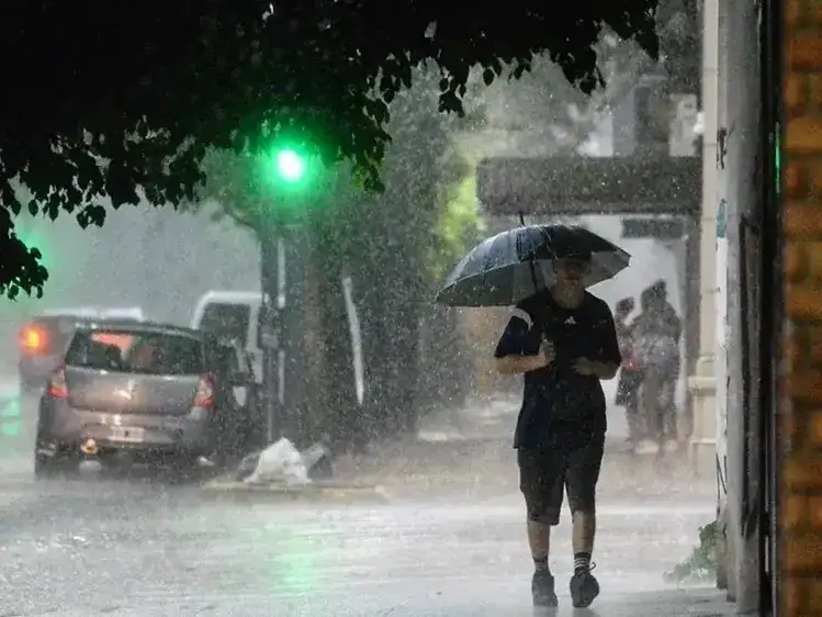 Un peatón camina bajo una intensa lluvia en las calles de Formosa, protegiéndose con un paraguas mientras rige la alerta amarilla por tormentas fuertes en la región. El mal tiempo afecta la circulación vehicular y peatonal durante la jornada.