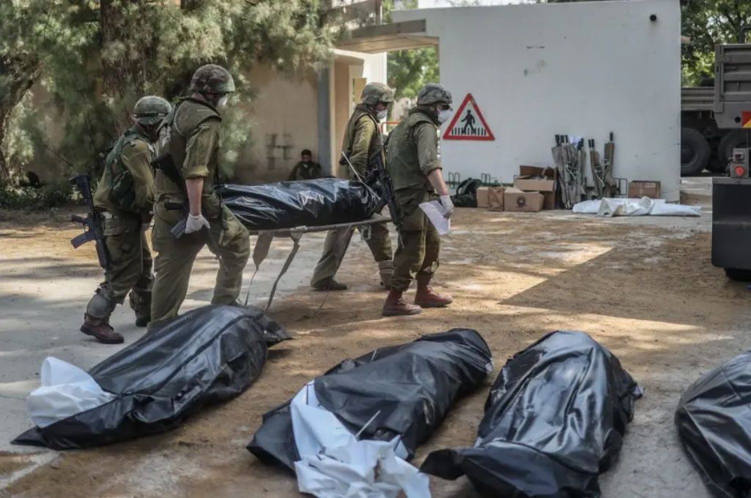 Los soldados israelíes trasladan los cuerpos de los asesinados en el kibutz Kfar Aza.