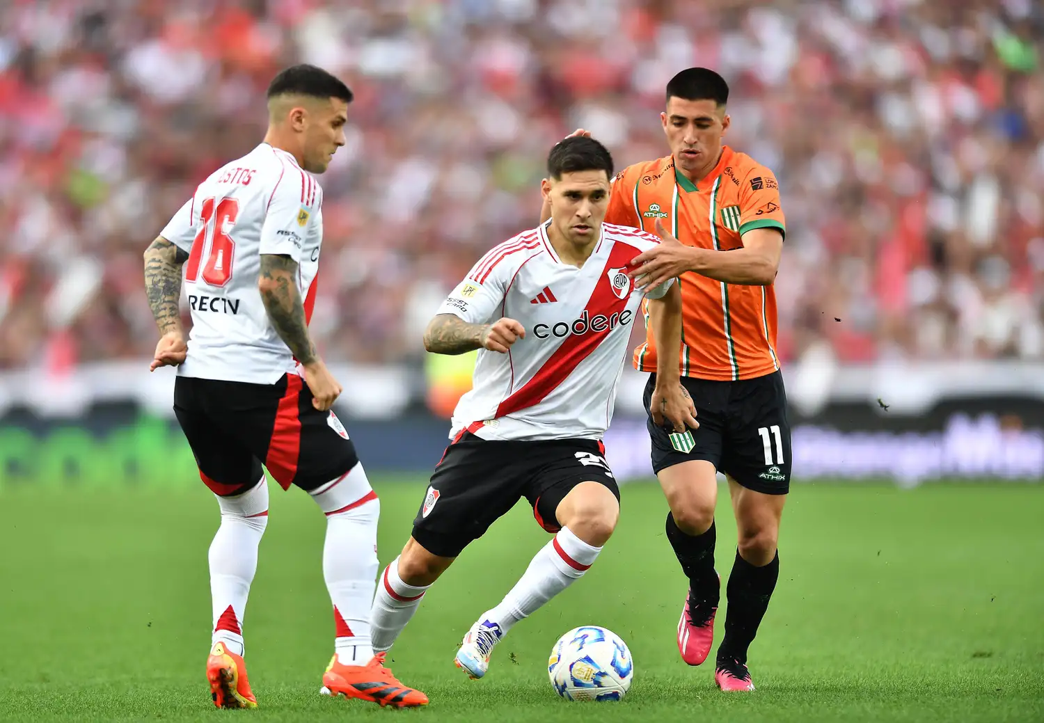 Villagra traslada el balón entre Bustos y Rodríguez.