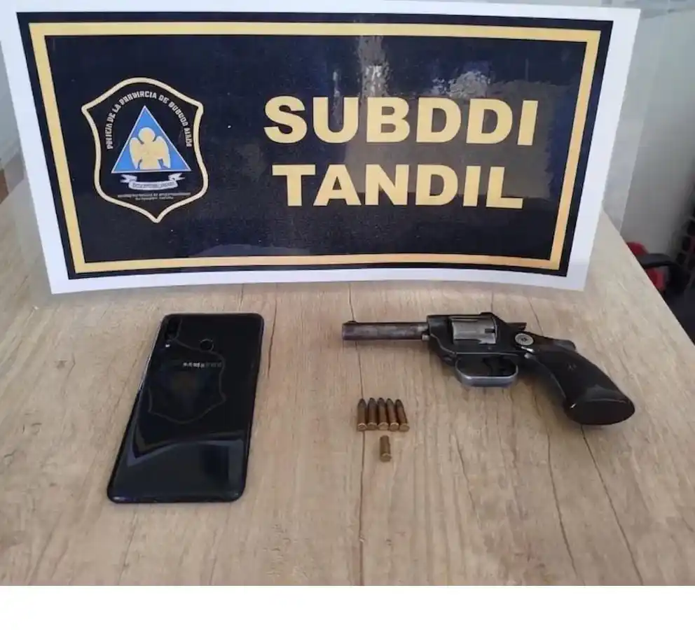 El celular y el arma que portaba el agresor apresado.