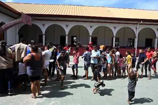 Evacuados de antiguas plantaciones bananeras tras el desbordamiento del río Ulúa por fuertes lluvias, hacen fila para recibir agua en la escuela Pedro Pascual Amaya, en el municipio El Progreso, departamento de Yoro, Honduras, el 26 de septiembre de 2022.