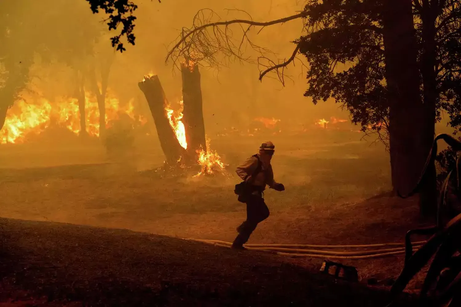 A firefighter runs while battling the Thompson Fire burning in Oroville, Calif., Tuesday, July 2, 2024