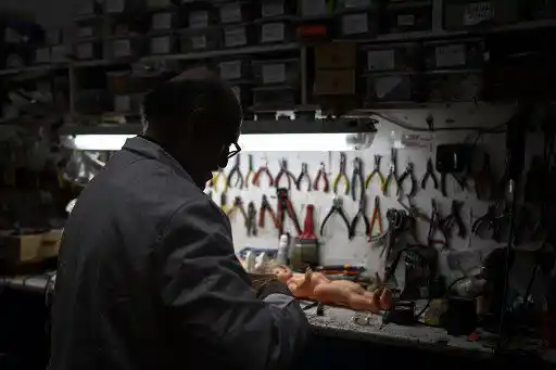 Antonio Martinez Rivas, de 70 años, recibe a un cliente en su taller "Hospital del Juguete", en Madrid el 20 de diciembre de 2022. - 