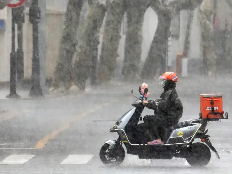 Un repartidor circula en una motocicleta bajo la lluvia. (Agencia Xinhua)