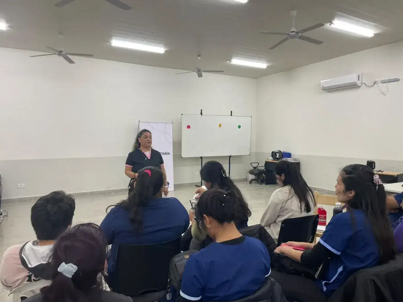 Una instructora brinda una capacitación sobre actualización en el cuidado infantil a un grupo de trabajadoras en Formosa, quienes participan activamente de la jornada formativa en un salón equipado para el aprendizaje profesional.
