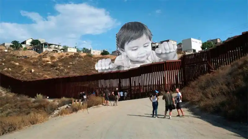 Artista "levanta a un niño gigante" que burla el muro y espía la frontera