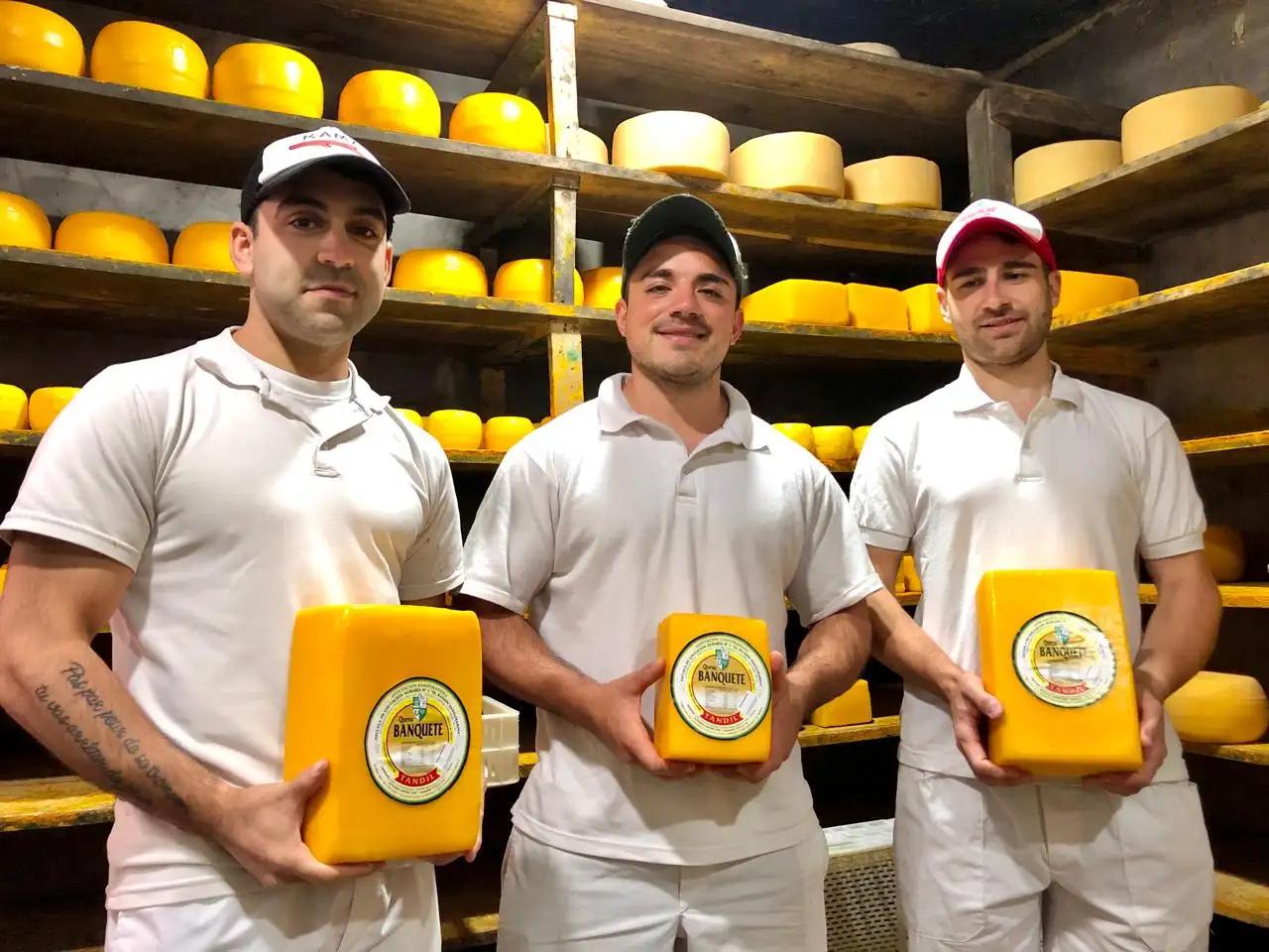 Enzo, al medio, junto a sus dos compañeros de la fábrica de la Escuela Granja, con el queso Banquete en sus manos.