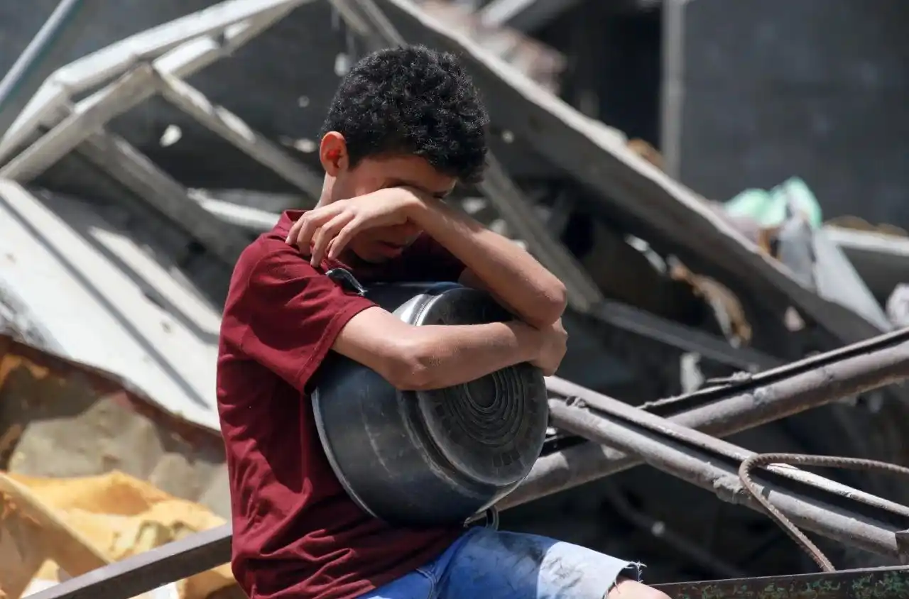 Un niño espera a que se distribuyan alimentos entre los palestinos desplazados de Yabalia, en el norte de la Franja de Gaza (Vatican News)