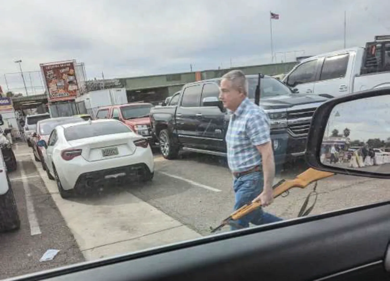 Mark Adams Prieto at a gun show in Phoenix with two rifles, one slung over his shoulder and another carried in his hand.