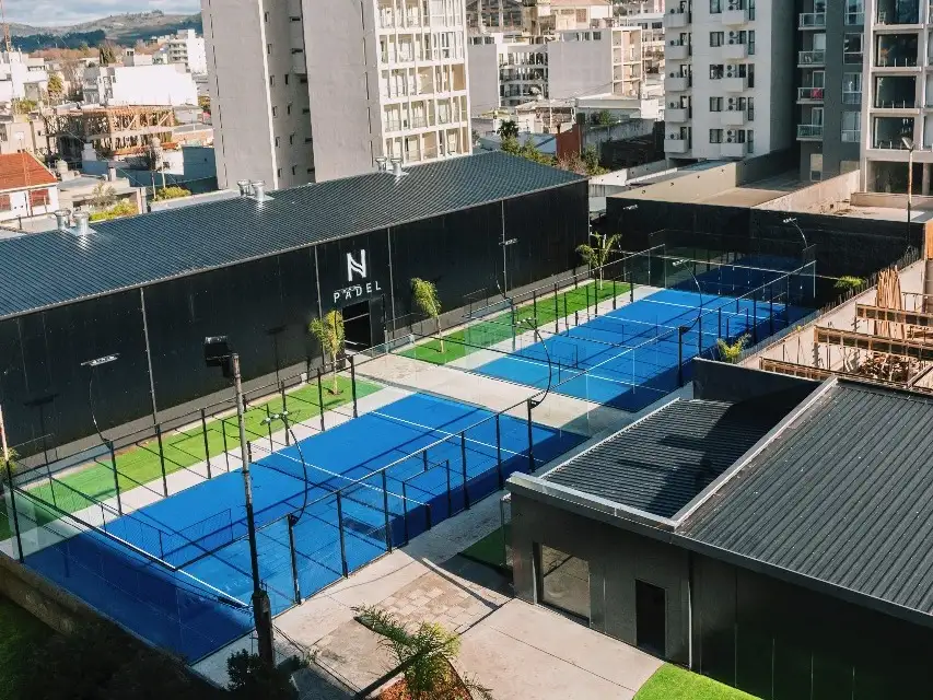 El corazón del complejo lo integran cuatro canchas de pádel profesionales: dos cubiertas con tecnología Blindex Full Panoramic, aislación acústica y climatización avanzada, y otras dos al aire libre.