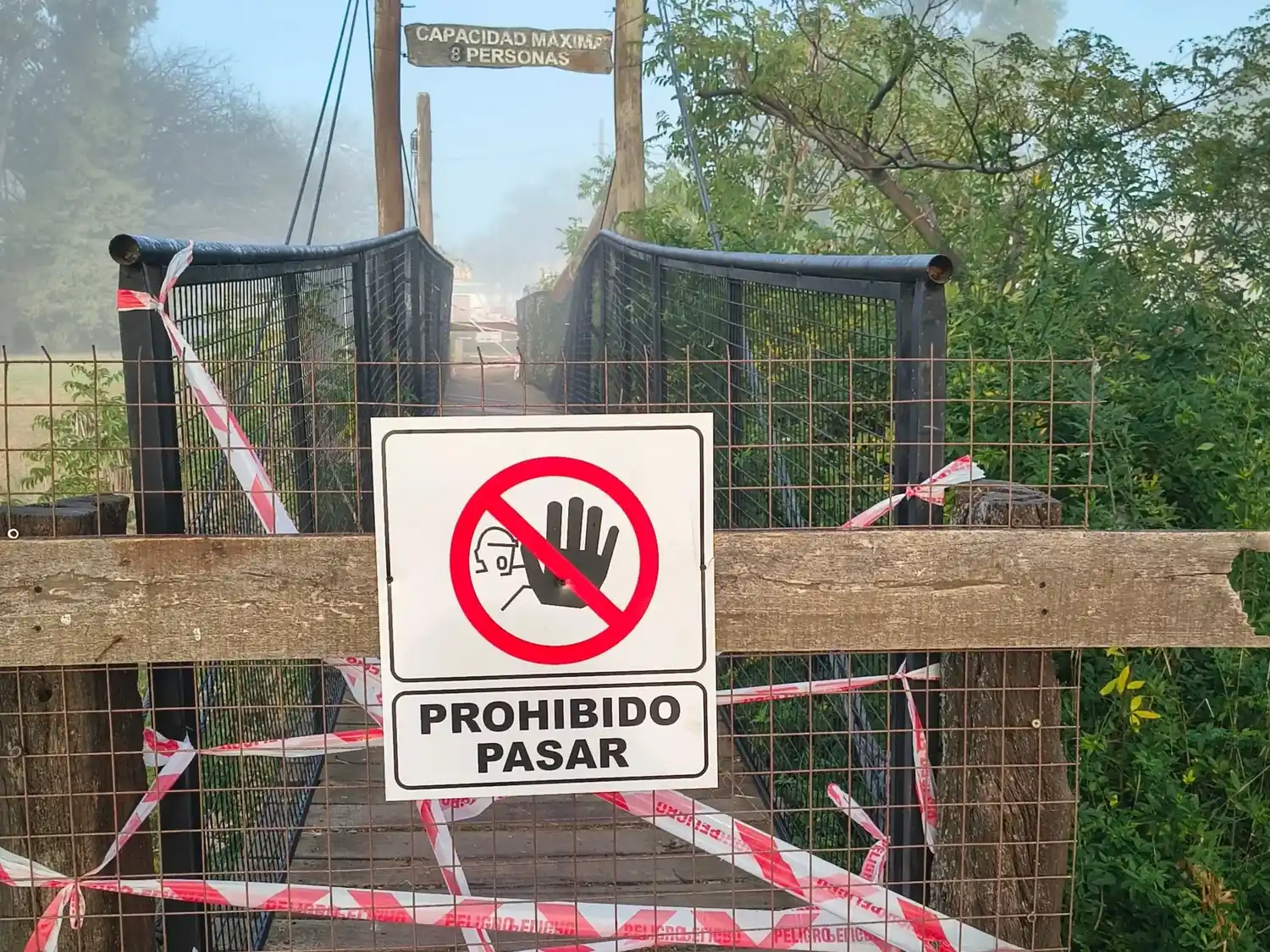 El puente tiene fajas que indican peligro y un cartel de prohibido pasar.