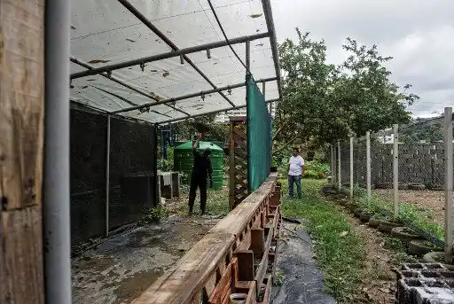 El director del proyecto "Lata de Agua", Laurencio Sánchez (D), revisa las tuberías de abastecimiento y los tanques de recolección de agua de lluvia en la escuela Unidad Educativa Nuestra Señora del Encuentro, beneficiaria del programa, en el populoso barrio de Petare en Caracas