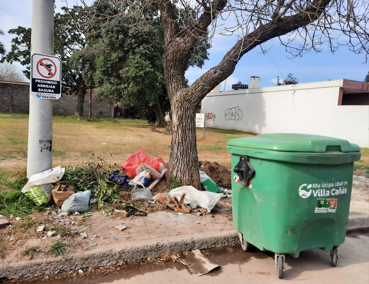 Las bolsas arrojadas denajo del cartel que reza "Prohibido arrojar basura".