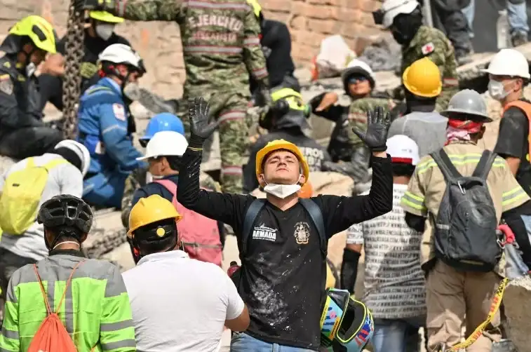 Un rescatista reacciona mientras busca sobrevivientes entre los escombros de un edificio colapsado.