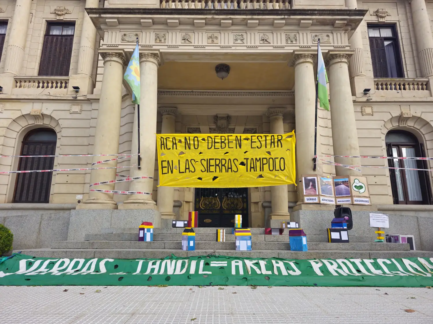 Se colocaron edificios y viviendas de cartón en las escalinatas del lugar, debajo de un pasacalles que expresa “Acá no deben estar, en las sierras tampoco”.