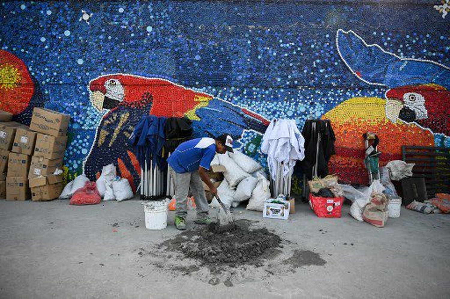 Un trabajador mezcla cemento para usar en un mural hecho con tapas de botellas de plástico por el artista venezolano Oscar Olivares en Guatire, estado de Miranda, Venezuela, el 13 de septiembre de 2022.
