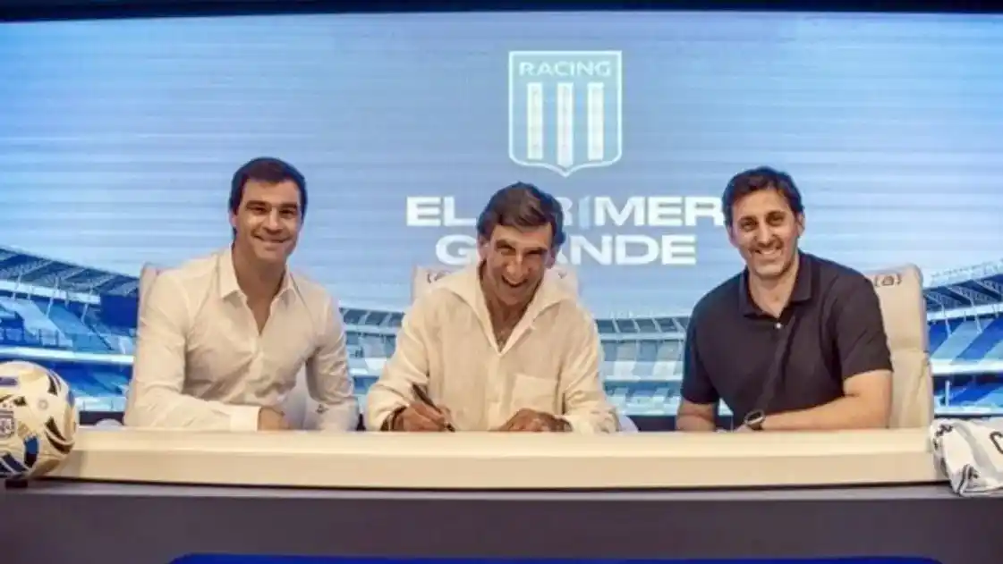 Costas pone la firma, con Sebastián Saja (director deportivo) a su derecha y el presidente Diego Milito. Fotos: Racing Club.