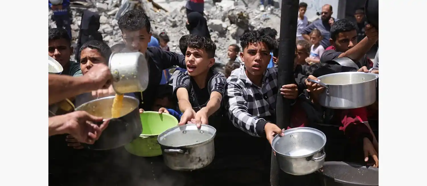 Palestinos desplazados se reúnen para recolectar porciones de comida en una distribución benéfica en Jabalia, al norte de Gaza, el 19 de mayo de 2025. BASHAR TALEB/AFP/AFP via Getty Images