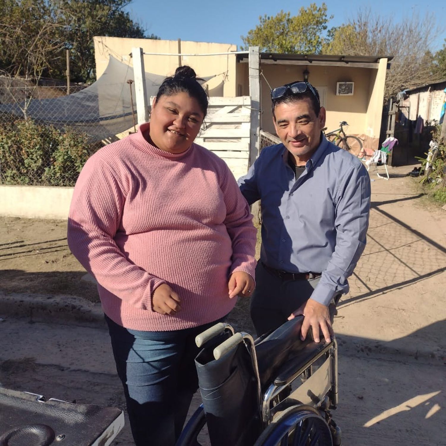 La hija de la beneficiada por la silla recibe la donación en manos de Guillermo Manzo.